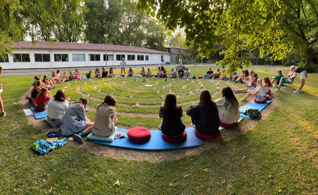 Groep kinderen en jongeren deelt een betekenisvol moment rond een spiraal van licht